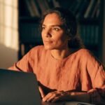 Pessoa analisando gráficos financeiros em celular e notebook, para o artigo Como conseguir uma renda extra: guia prático p...