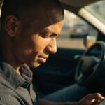 Pessoa analisando gráficos financeiros em celular e notebook, para o artigo Empréstimo para Motoristas de Aplicativo: Guia...