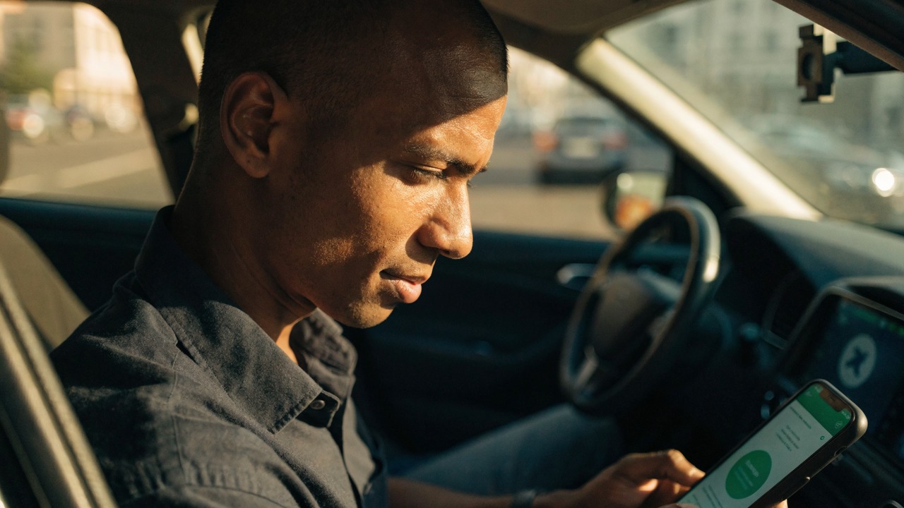Pessoa analisando gráficos financeiros em celular e notebook, para o artigo Empréstimo para Motoristas de Aplicativo: Guia...