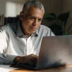 Profissional usando notebook com painéis de dados e interface digital, para o artigo Receita paga R$ 16 bi no 2º lote do I...