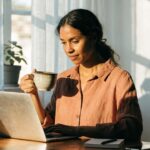 Pessoa analisando gráficos financeiros em celular e notebook, para o artigo Renda Extra Online: Guia Completo com Ideias C...