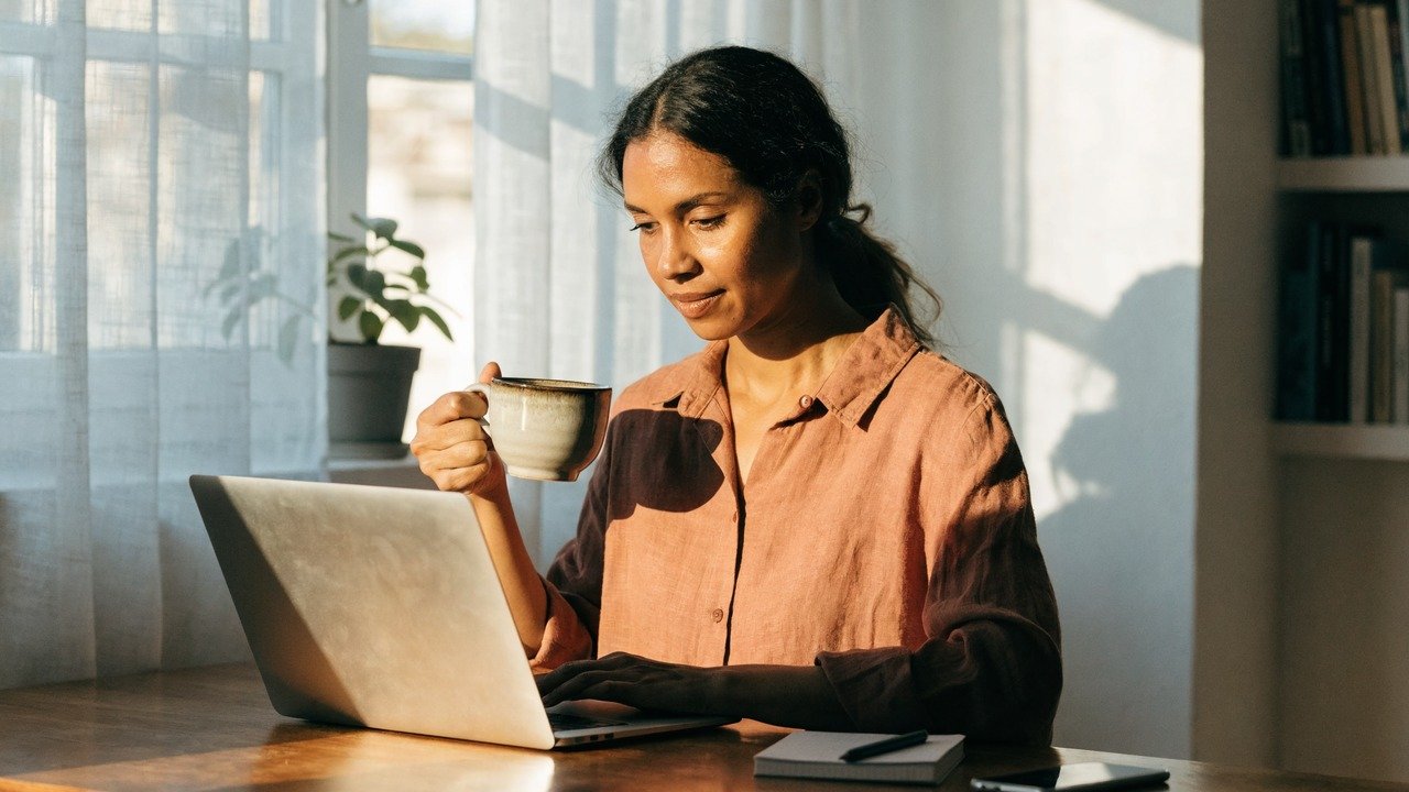Pessoa analisando gráficos financeiros em celular e notebook, para o artigo Renda Extra Online: Guia Completo com Ideias C...