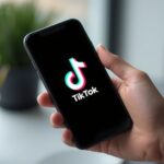 Pessoa brasileira trabalhando em ambiente digital profissional no notebook e no celular para ilustrar Como começar no TikTok Shop como.