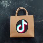 Pessoa brasileira trabalhando em ambiente digital profissional no notebook e no celular para ilustrar Como ganhar comissão no TikTok Shop.
