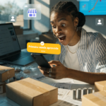 Mulher sorridente olha para o celular com notificação de primeira venda aprovada, cercada por caixas de encomendas.